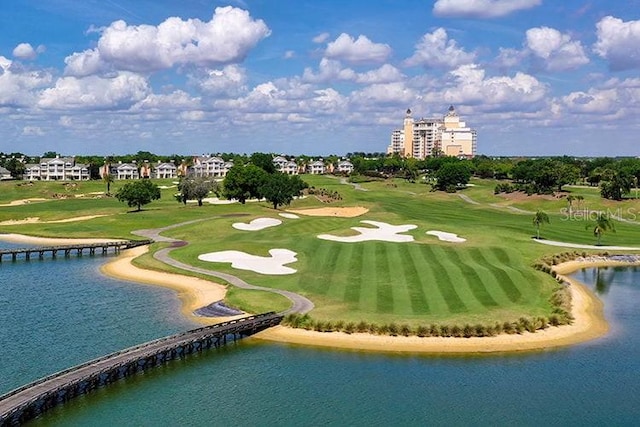 view of property's community with view of golf course, a yard, and a water view