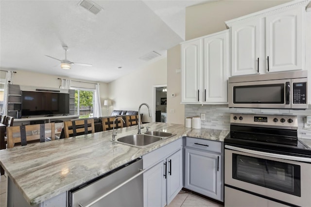 kitchen with light stone counters, ceiling fan, kitchen peninsula, stainless steel appliances, and sink