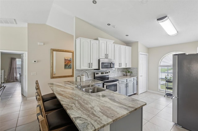 kitchen with light tile patterned floors, kitchen peninsula, stainless steel appliances, and vaulted ceiling