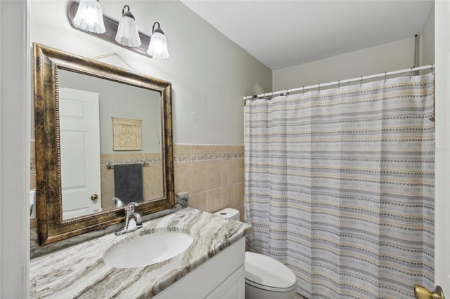 bathroom with tile walls, vanity, and toilet