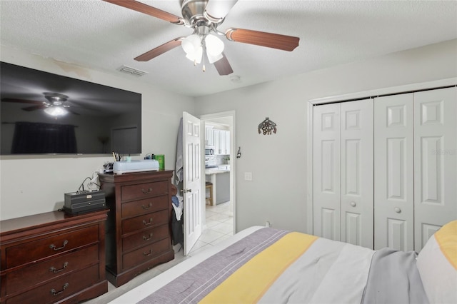 bedroom with light tile patterned flooring, a textured ceiling, a closet, and ceiling fan