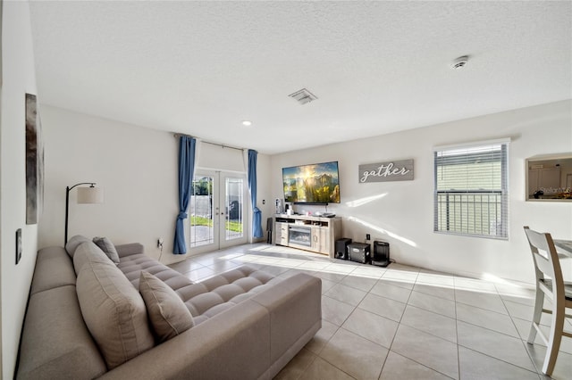 living room with a wealth of natural light, french doors, light tile patterned floors, and a textured ceiling