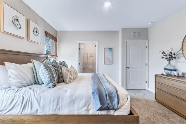 bedroom featuring light colored carpet, a closet, and a spacious closet