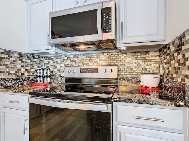 kitchen with white cabinets, decorative backsplash, dark stone counters, and stainless steel appliances