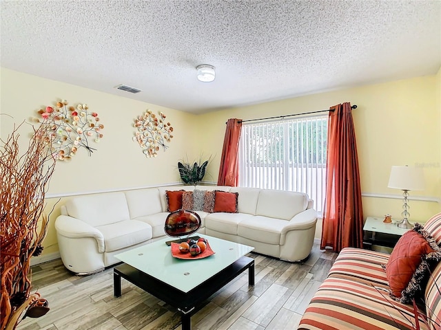 living room with light wood-type flooring and a textured ceiling