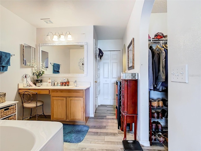 bathroom with hardwood / wood-style floors, a bath, and vanity