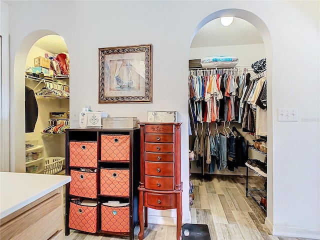 walk in closet with light hardwood / wood-style floors