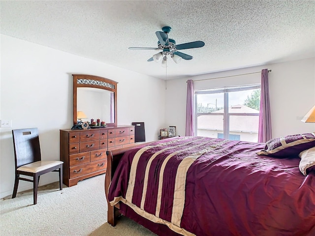 carpeted bedroom featuring ceiling fan and a textured ceiling