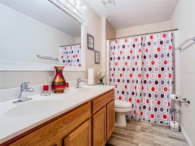 bathroom featuring toilet, dual vanity, and hardwood / wood-style flooring