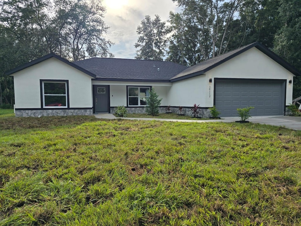 ranch-style home with concrete driveway, a front lawn, an attached garage, and stucco siding