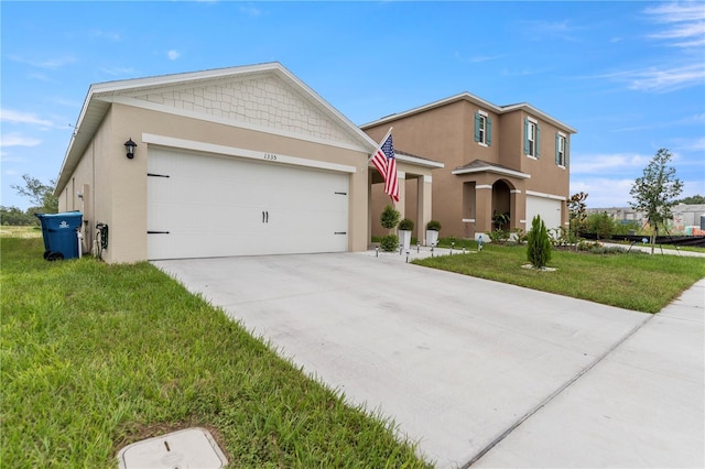 view of front of home with a garage, a front yard, concrete driveway, and stucco siding