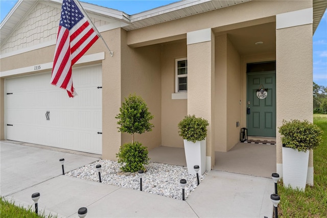 doorway to property with a garage, driveway, and stucco siding