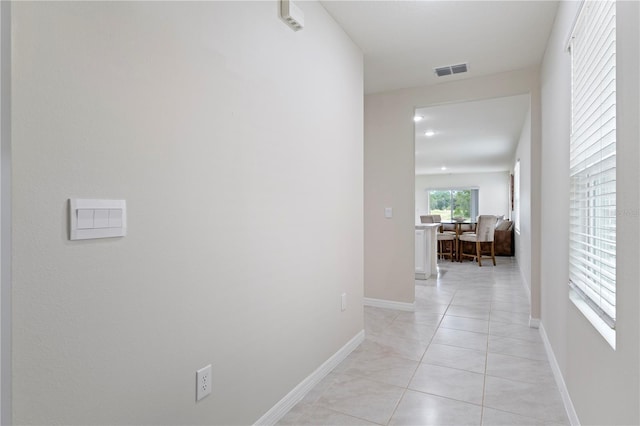 corridor featuring light tile patterned floors, baseboards, and visible vents