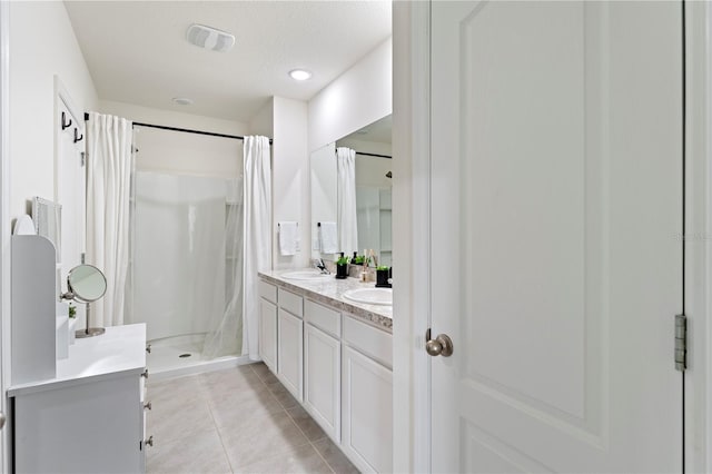 bathroom featuring double vanity, a stall shower, a sink, and tile patterned floors