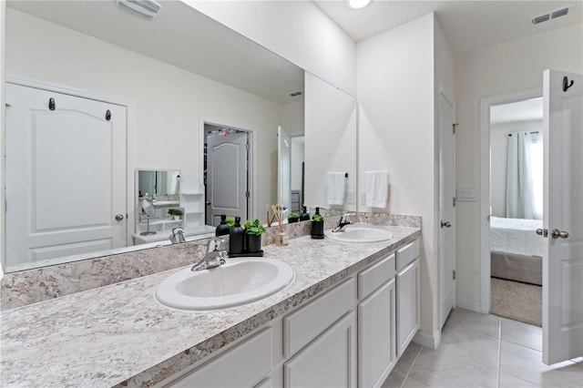 bathroom with connected bathroom, visible vents, a sink, and double vanity