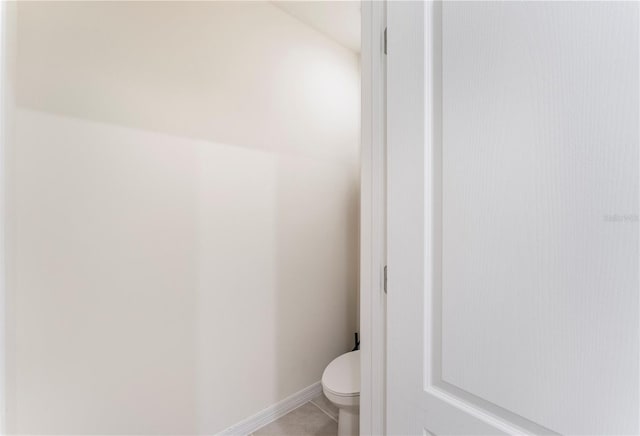 bathroom with toilet, baseboards, and tile patterned floors