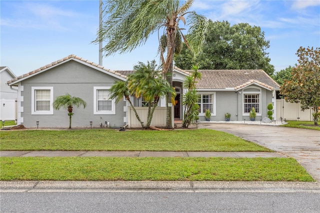 single story home featuring a tile roof, a front lawn, and stucco siding