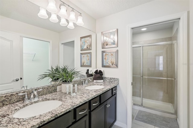 bathroom featuring tile patterned floors, a textured ceiling, dual vanity, and an enclosed shower