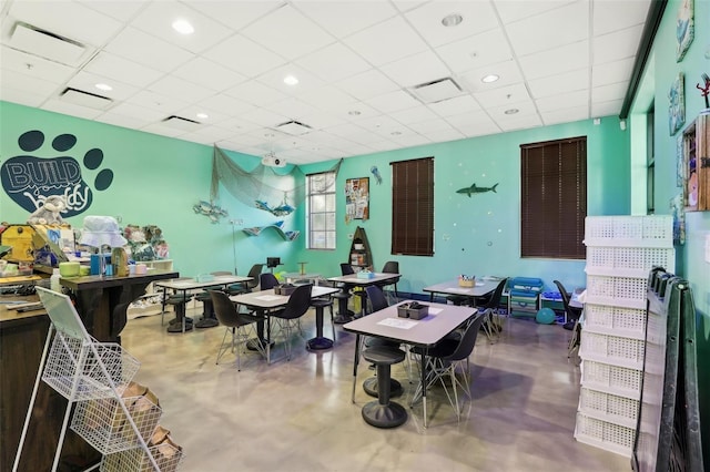 rec room with a paneled ceiling and concrete flooring