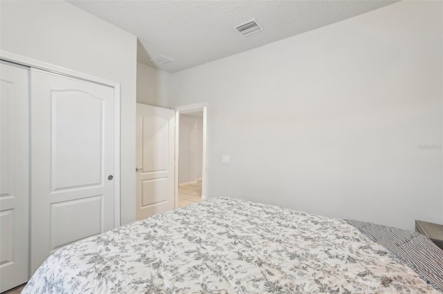 tiled bedroom with a closet and a textured ceiling