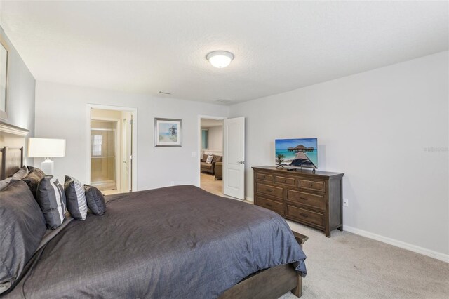 bedroom with connected bathroom and light carpet