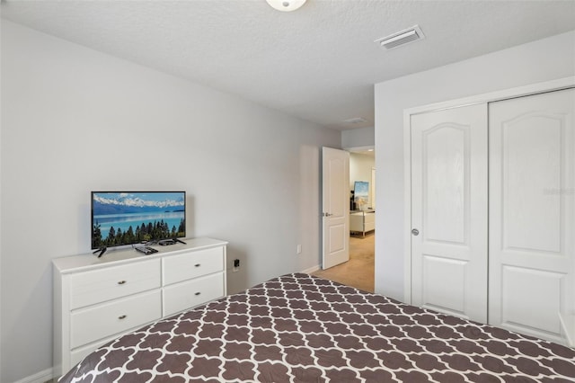 bedroom with a closet, light carpet, and a textured ceiling