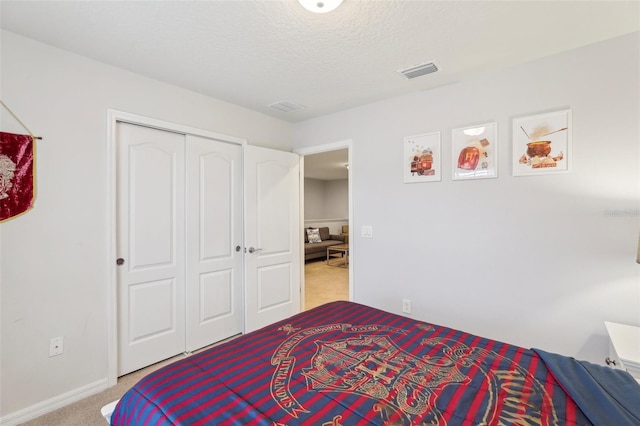 bedroom featuring light carpet, a textured ceiling, and a closet