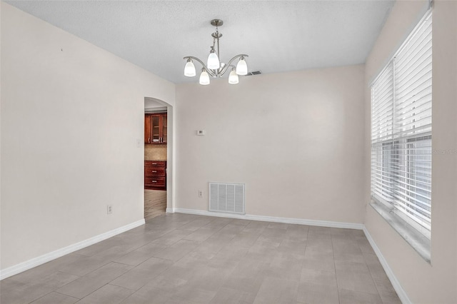 empty room with an inviting chandelier and a textured ceiling