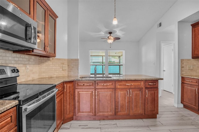 kitchen featuring lofted ceiling, sink, light stone counters, kitchen peninsula, and stainless steel appliances