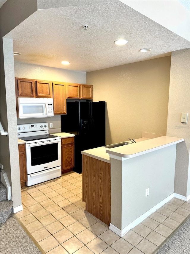 kitchen featuring a textured ceiling, white appliances, and light tile patterned floors