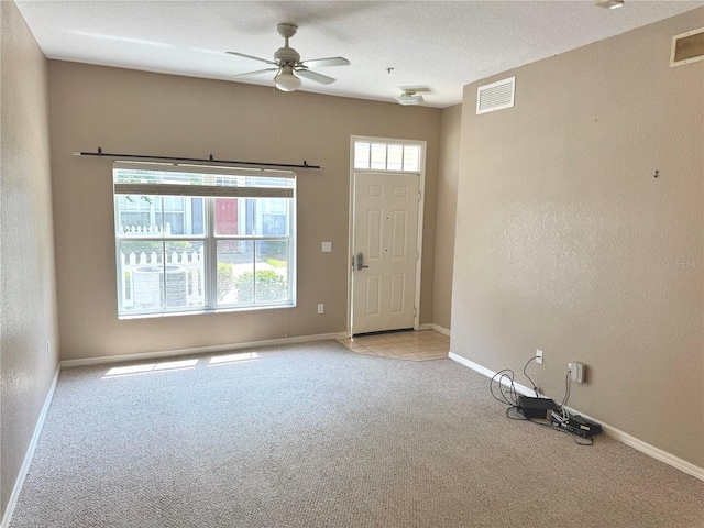 empty room with light carpet, a textured ceiling, and ceiling fan