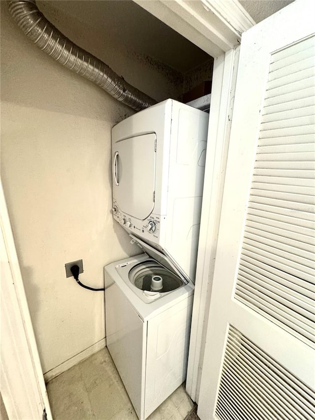 clothes washing area with stacked washer and dryer and light tile patterned floors