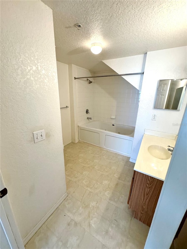 bathroom with tiled shower / bath combo, vanity, a textured ceiling, and tile patterned flooring