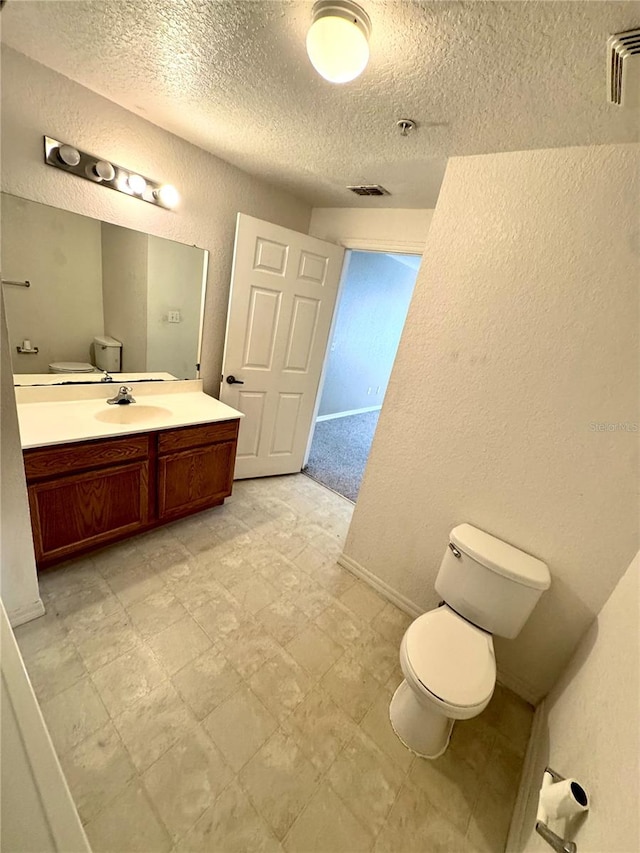 bathroom featuring vanity, tile patterned floors, a textured ceiling, and toilet