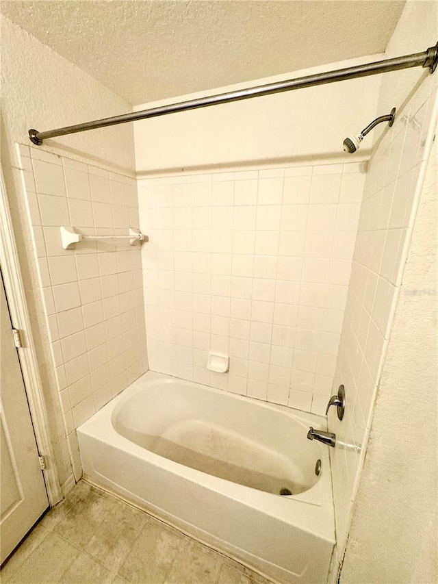 bathroom featuring tile patterned floors, tiled shower / bath combo, and a textured ceiling