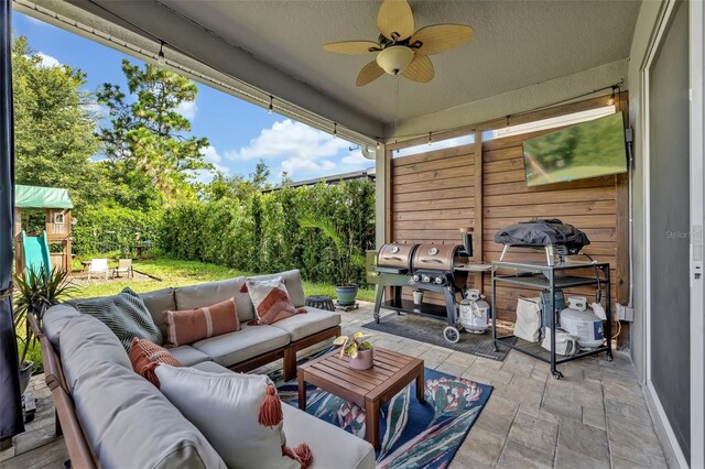 view of patio with an outdoor living space, area for grilling, ceiling fan, and a playground