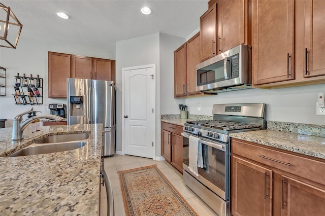 kitchen featuring stainless steel appliances, sink, light tile patterned floors, and light stone counters