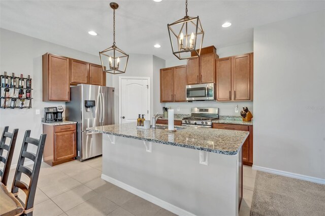 kitchen with sink, hanging light fixtures, a kitchen breakfast bar, an island with sink, and stainless steel appliances