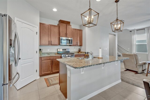 kitchen with a kitchen bar, sink, light stone counters, hanging light fixtures, and stainless steel appliances