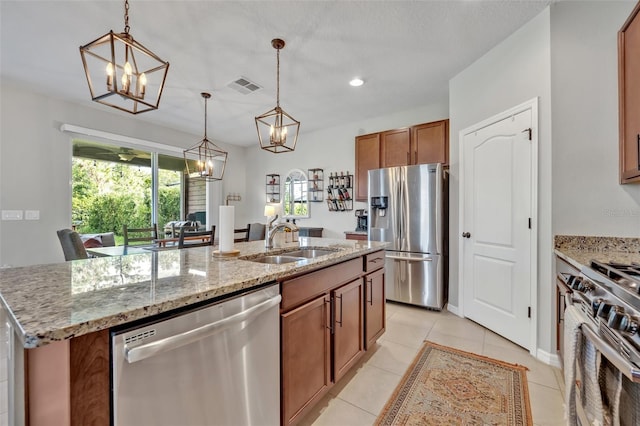 kitchen featuring sink, a chandelier, hanging light fixtures, appliances with stainless steel finishes, and a kitchen island with sink