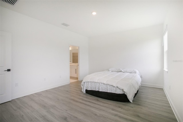 bedroom featuring ensuite bath and wood-type flooring