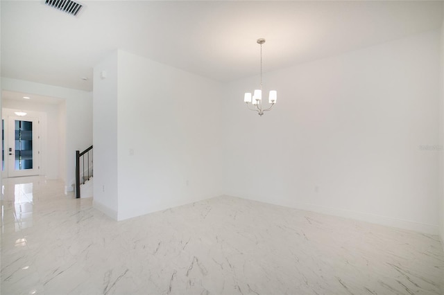 unfurnished room featuring a chandelier