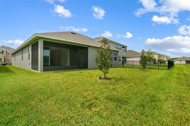 rear view of property featuring a sunroom and a lawn