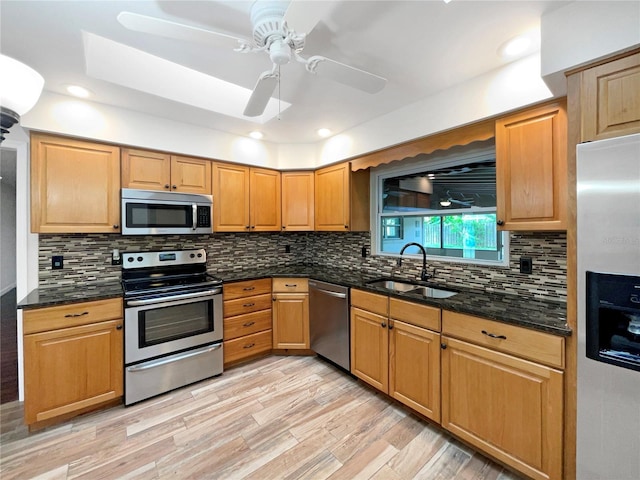 kitchen featuring ceiling fan, stainless steel appliances, sink, light hardwood / wood-style floors, and backsplash