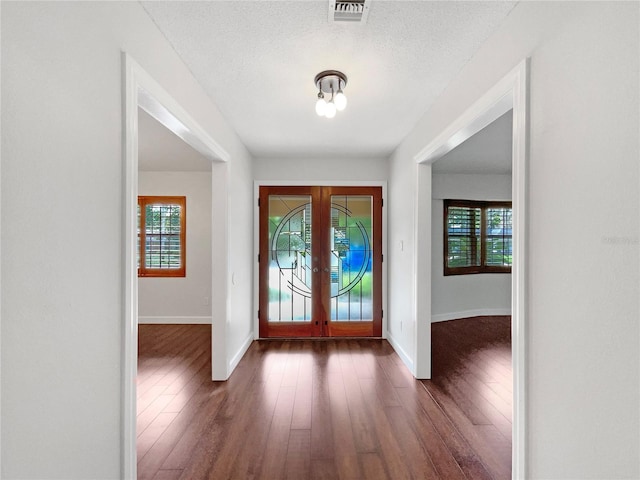 entrance foyer featuring dark hardwood / wood-style flooring, a textured ceiling, french doors, and plenty of natural light