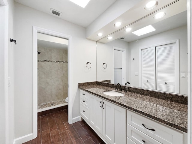 bathroom with vanity, toilet, and a tile shower