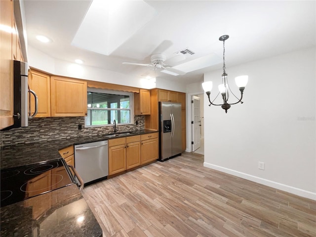 kitchen featuring ceiling fan with notable chandelier, light wood-type flooring, sink, appliances with stainless steel finishes, and backsplash