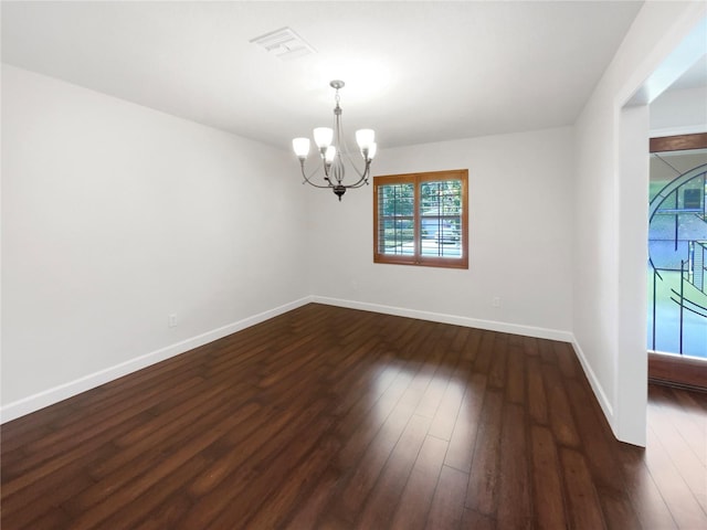 empty room with dark hardwood / wood-style flooring and a chandelier