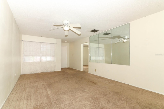 carpeted empty room featuring ceiling fan, visible vents, and a textured ceiling