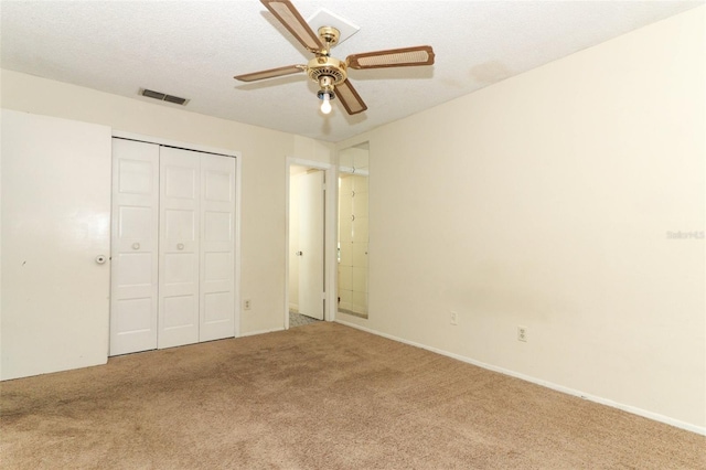 unfurnished bedroom featuring a textured ceiling, ceiling fan, visible vents, a closet, and carpet